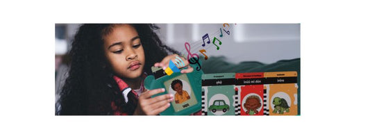 Young girl playing with Tribal Tongue Talking Flashcards device, learning Yoruba words with colourful illustrated cards and music notes.