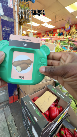 Young kid playing with Yoruba Talking Flashcards, putting the cards up against the real items like bike and yam.
