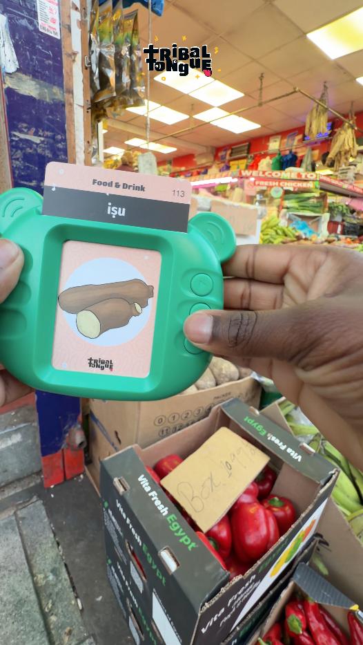 Young kid playing with Yoruba Talking Flashcards, putting the cards up against the real items like bike and yam.